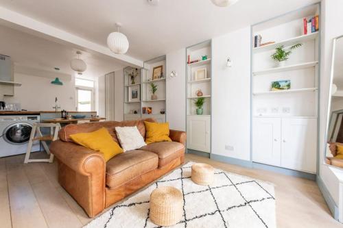 a living room with a brown couch and a kitchen at Lovely self-contained basement studio with kitchen in London