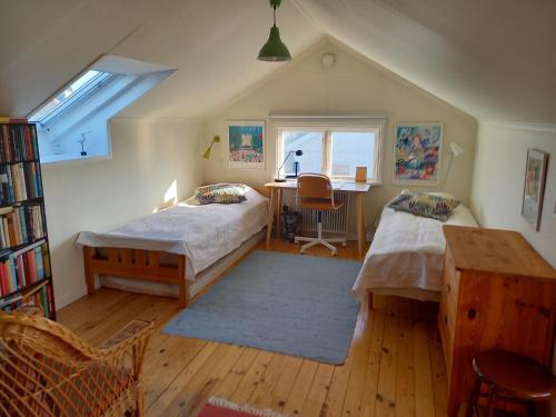 a attic bedroom with two beds and a desk at Ljust boende, egen ingång och trädgård i centrum in Varberg