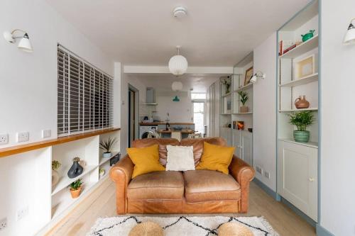 a living room with a brown couch and yellow pillows at Lovely self-contained basement studio with kitchen in London
