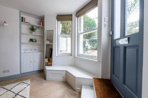 a room with a bench in front of two windows at Lovely self-contained basement studio with kitchen in London