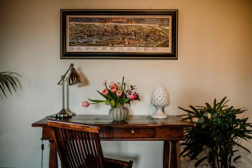 a desk with a vase of flowers and a picture on the wall at Villa Medicea di Lilliano in Grassina