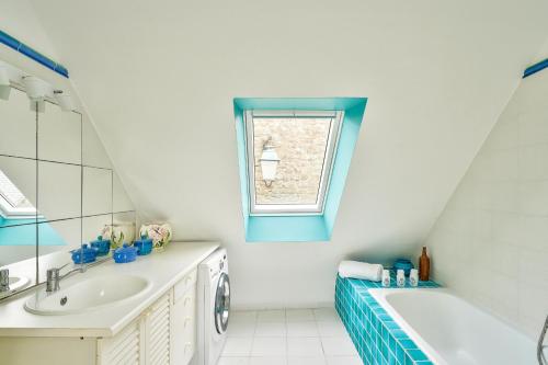 La salle de bains est pourvue d'un lavabo, d'une baignoire et d'une fenêtre. dans l'établissement À 30 m de la mer - Maison pour 7 à l' Île Tudy, à l'Île-Tudy