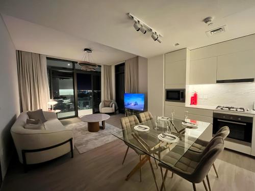a living room with a glass table and a kitchen at Palace Dubai Creek Harbour Residences Skyline Apartment in Dubai