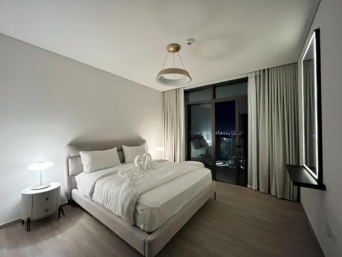 a white bedroom with a large bed and a window at Palace Dubai Creek Harbour Residences Skyline Apartment in Dubai