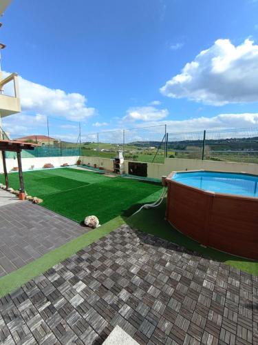 un patio trasero con piscina y césped verde en Sossego e tranquilidade - Valley Guest House - Perto de Lisboa, en Arruda dos Vinhos