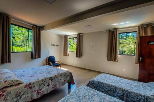 1 Schlafzimmer mit 2 Betten, Fenstern und einem Stuhl in der Unterkunft Lua Branca_Recanto in Juiz de Fora