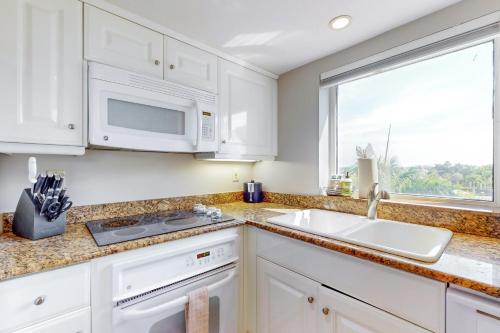 a kitchen with white cabinets and a sink and a window at Marco Beach Ocean Resort 601 in Marco Island