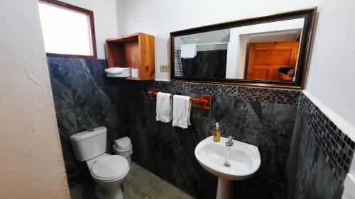 a bathroom with a toilet and a sink and a mirror at Alma de cedrela in Puerto Ayora