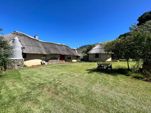 a house with a thatched roof with a picnic table in the yard at Mpofu Lodge in Bergview