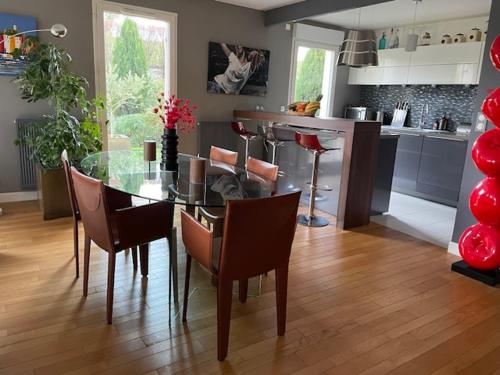 une salle à manger avec une table et des chaises en verre dans l'établissement appartement + jardin privatif, à Versailles