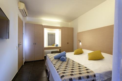 a bedroom with two beds with yellow and blue pillows at Atlantica Mikri Poli Kos in Kardamaina