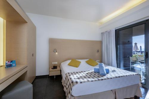 a hotel room with a bed and a large window at Atlantica Mikri Poli Kos in Kardamaina