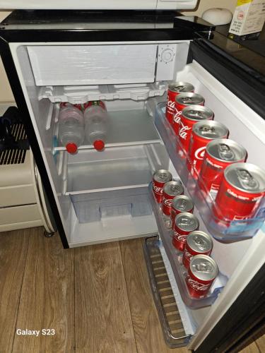 an open refrigerator with sodas and cans of soda at Cool place in Ramat Gan in Ramat Gan
