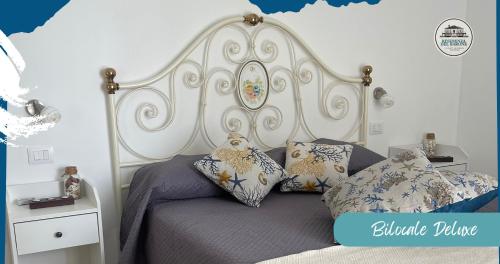 Residenza del Barone Luxury House - Pula, Sardegna في بولا: غرفة نوم مع سرير مع اللوح الأمامي الأبيض والوسائد