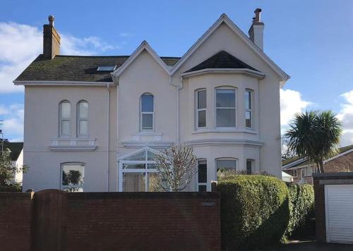 a white house with a fence in front of it at Dog friendly home close to the beach and the town in Exmouth