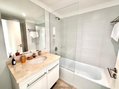 a white bathroom with a sink and a shower at Apartamento centrico con vistas panoramicas Puerto Iguazu in Puerto Iguazú