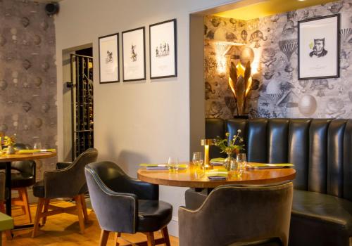 une salle à manger avec des tables et des chaises ainsi qu'un mur recouvert de papier peint. dans l'établissement The Queensberry Hotel, à Bath