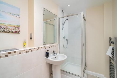 uma casa de banho branca com um lavatório e um chuveiro em Spacious Penthouse - Sleeps 6, Ideal for Contractors, Families & Business Travellers - Free Parking em Watford