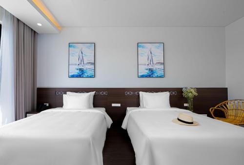 two beds in a hotel room with a hat at Hoang Yen Boutique Hotel in Dien Ban