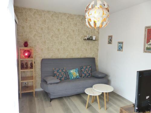 ein Wohnzimmer mit einem blauen Sofa und einem Kronleuchter in der Unterkunft LA PETITE MAISON TAHET, 2 pers avec terrasse in Basse-Indre