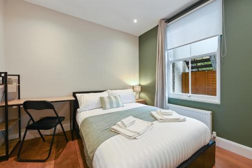 a bedroom with a bed with a desk and a window at Stunning 2 Bed basement flat in Hammersmith in London