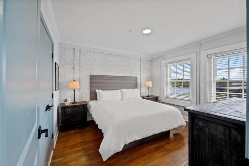 a white bedroom with a large bed and two lamps at Discover Conway Trendy Downtown Loft in Conway