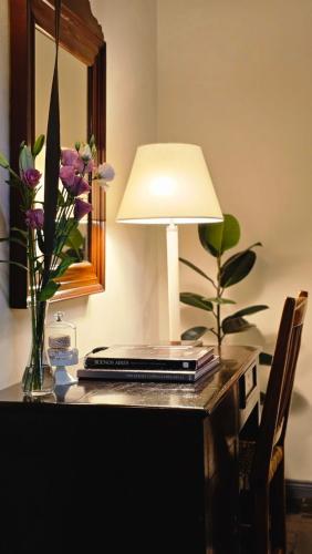 a laptop on a desk with a lamp and flowers at BE Jardin Escondido By Coppola in Buenos Aires