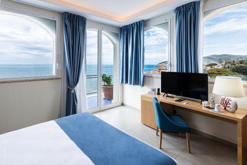 a hotel room with a bed and a desk with a television at Grand Hotel Santa Maria in Santa Maria di Castellabate