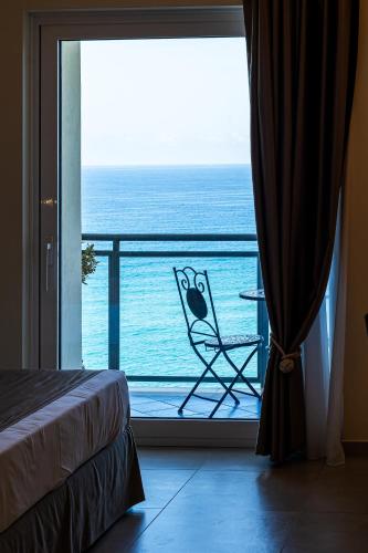 a room with a balcony with a chair and the ocean at Grand Hotel Santa Maria in Santa Maria di Castellabate