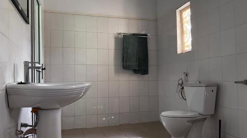 a white bathroom with a toilet and a sink at Lodge Jamarek in Kafountine