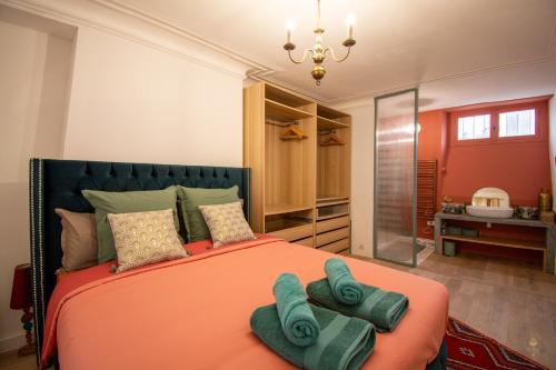 - une chambre avec un lit orange et des serviettes dans l'établissement Wonderful typical Paris flat 3 bedrooms / 6 pax, à Paris
