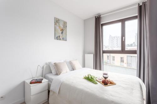 a white bedroom with a bed with a tray of food on it at Warsaw City Apartments in Warsaw