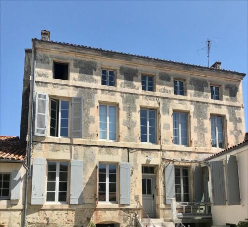 - un vieux bâtiment en pierre avec des portes et des fenêtres blanches dans l'établissement The Apartment, à Saint-Jean-dʼAngély