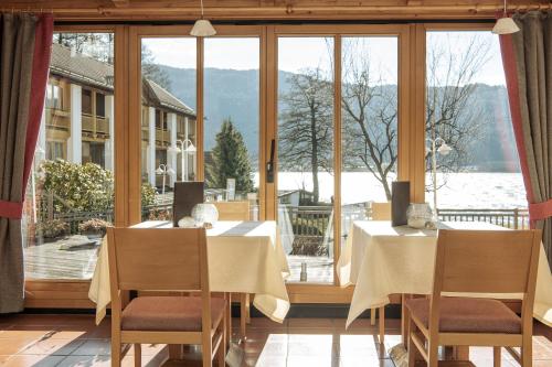 a dining room with two tables and a large window at Seehotel Urban in Bodensdorf