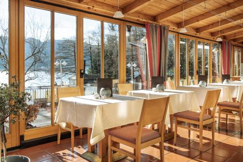 a dining room with tables and chairs and windows at Seehotel Urban in Bodensdorf