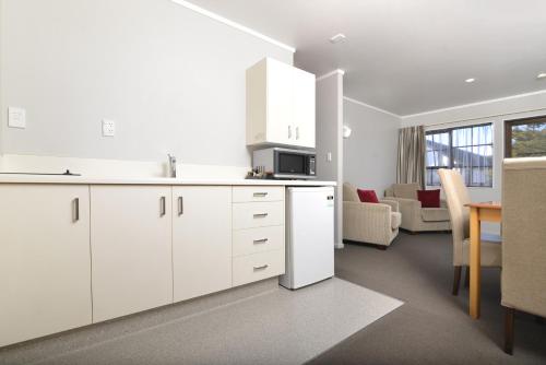 a kitchen with white cabinets and a living room at Knightsbridge Court Motor Lodge in Blenheim