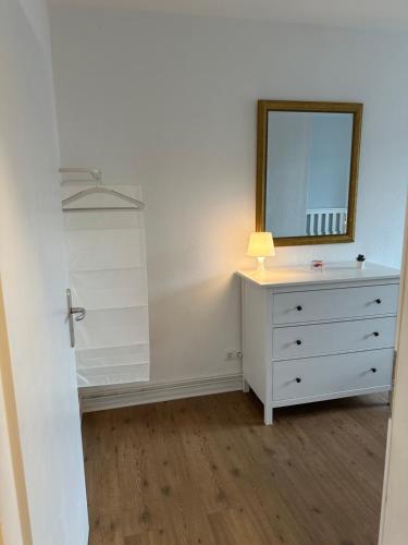a bedroom with a dresser with a mirror and a lamp at Ferienwohnung Hansetraum Lübeck in Lübeck