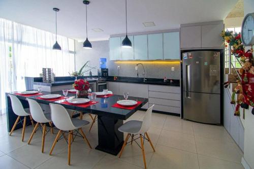 eine Küche mit einem Tisch mit Stühlen und einem Kühlschrank in der Unterkunft Casa c/piscina á 15 minutos Parque Beto Carreiro e 300m da praia Navegantes in Navegantes