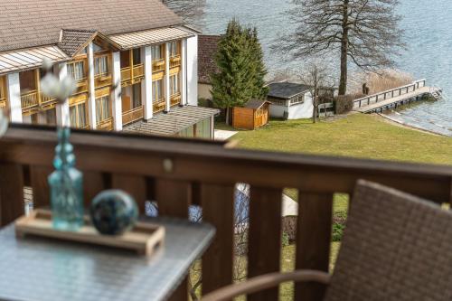 a balcony with a view of a house and the water at Seehotel Urban in Bodensdorf
