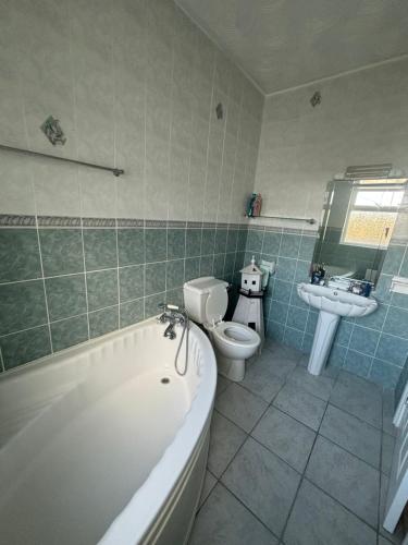 uma casa de banho com uma banheira, um WC e um lavatório. em Seaview Bungalow em Donegal