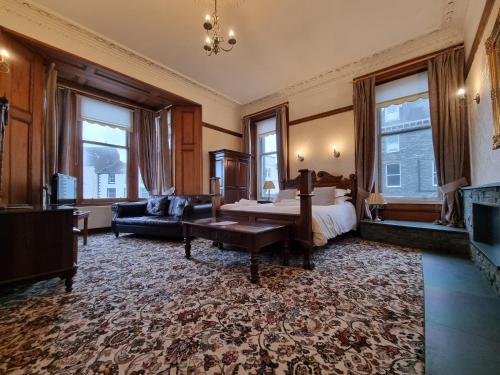 a bedroom with a bed and a couch and windows at Keswick Park Hotel in Keswick