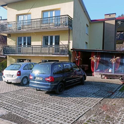 two cars parked in a parking lot in front of a building at Pokoje u Danuty in Piwniczna-Zdroj