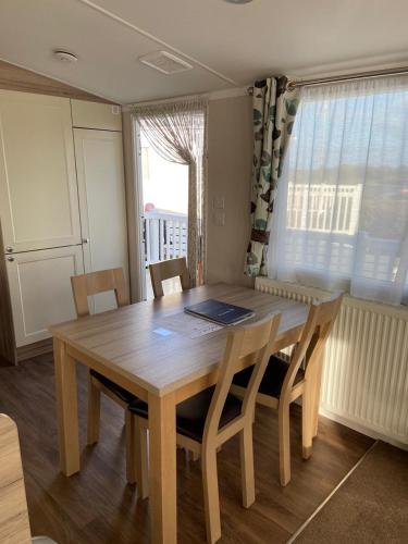 a wooden table and chairs in a room with a window at Ger-Y-Bwlch - Spacious static on 5star site with Swimming Pool in Benllech