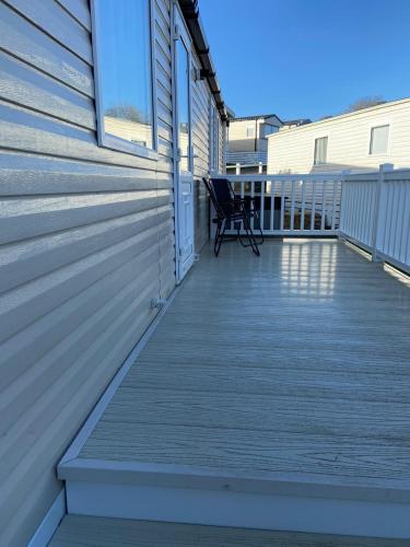 a deck with a chair on the side of a house at Ger-Y-Bwlch - Spacious static on 5star site with Swimming Pool in Benllech
