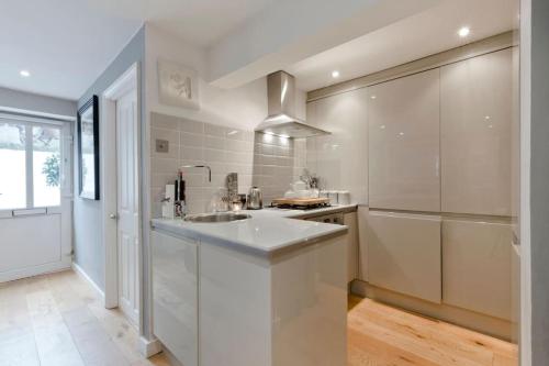een witte keuken met een wastafel en een koelkast bij Windsor Royal Retreat Luxury 1BED Apartment in Windsor