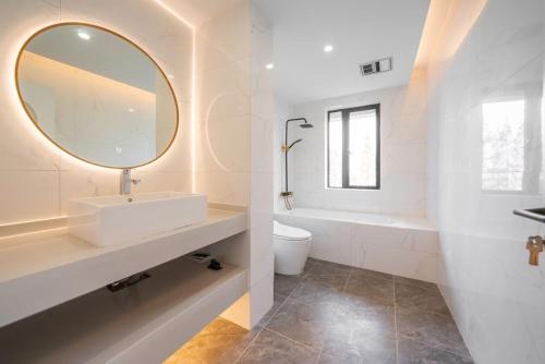 a white bathroom with a sink and a mirror at Shanghai Hills & Serendipity Homestay in Shanghai