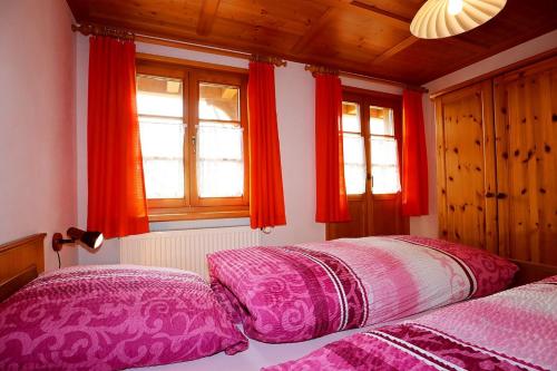 twee bedden in een slaapkamer met rode gordijnen bij Haus Rosa in Todtmoos