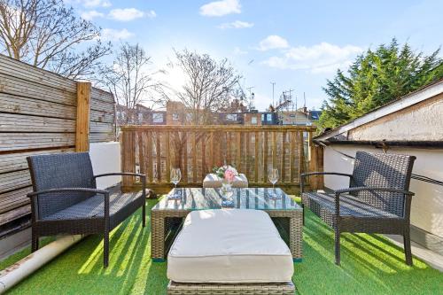 a patio with two chairs and a table on the grass at Balcony Blue Theme 1 Bedroom Central London Luxury Flat Near Hyde Park! Accommodates up to 6! Double Sofa Bed and Next to Station! in London