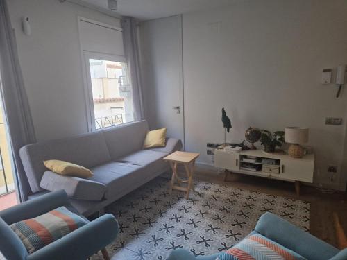 ein Wohnzimmer mit einem blauen Sofa und 2 Stühlen in der Unterkunft Cozy sunny apartment in the heart of Barcelona in Barcelona
