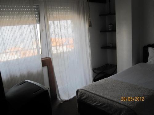 a bedroom with a bed and two large windows at Hotel Portofoz in Porto
